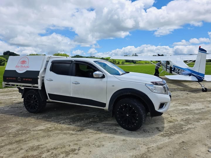 Auto Electricks branded service ute parked beside a ZK-registered light aircraft on an Otorohanga airstrip